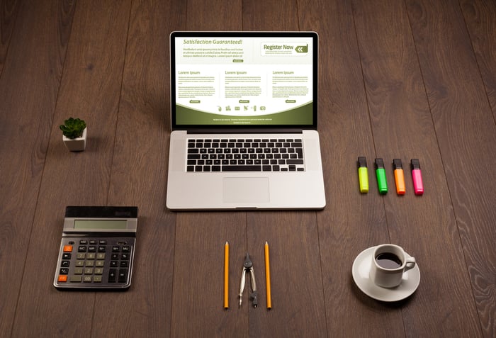 Workspace with a laptop computer, office accessories, and materials for an ecommerce website audit on a wooden table