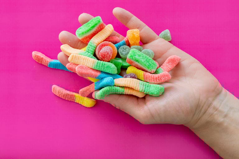 gummy worms and candies in the palm of a hand