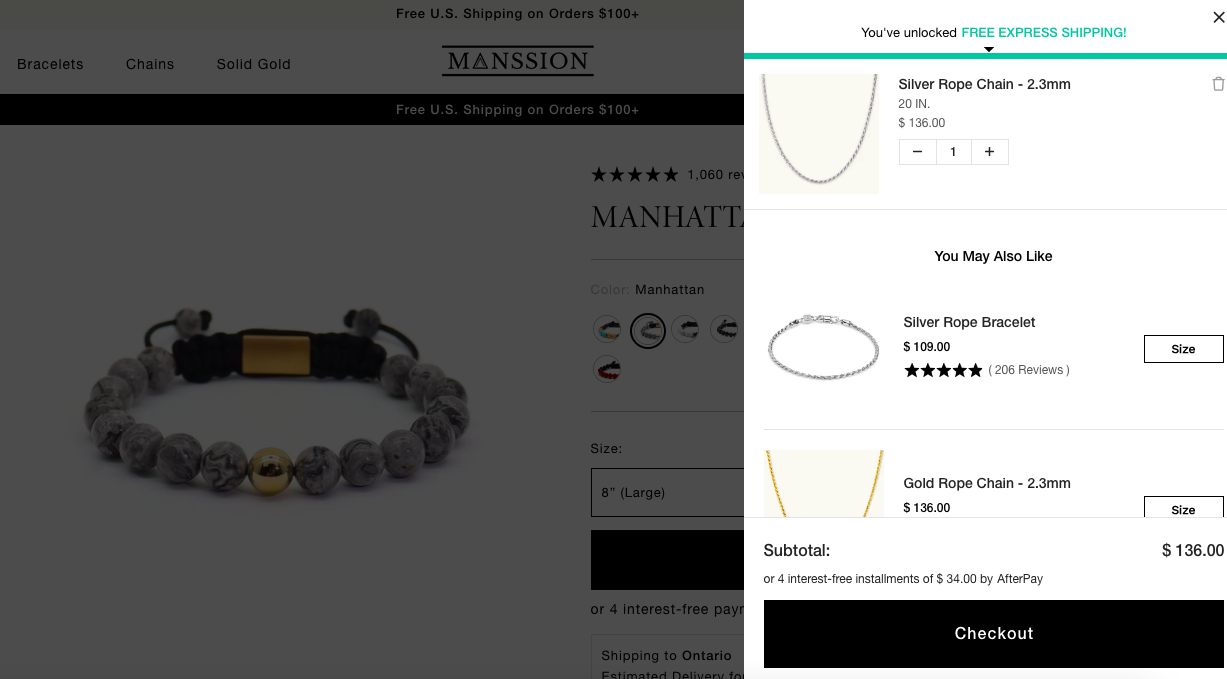 Screenshot of a men's jewelry brand online store, Manssion, which shows their cart with ai-powered product recommendations after a bracelet was added to cart and there are options for necklaces as well as a progress bar showing free shipping that is unlocked