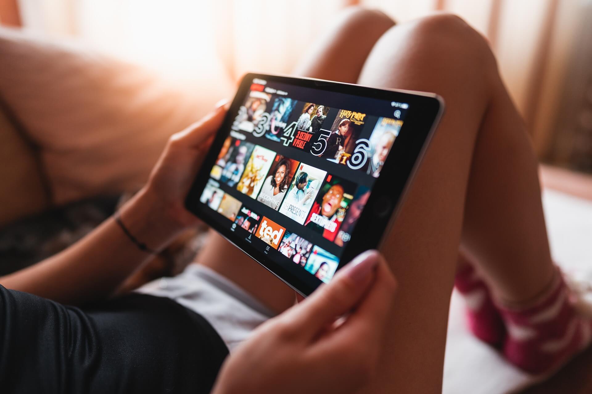 A young woman browses Netflix on an iPad.